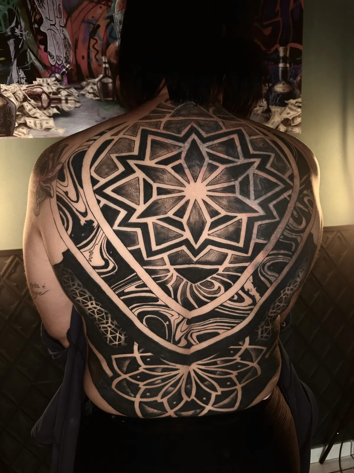 Tatuagem geométrica de mandala nas costas com simetria radial